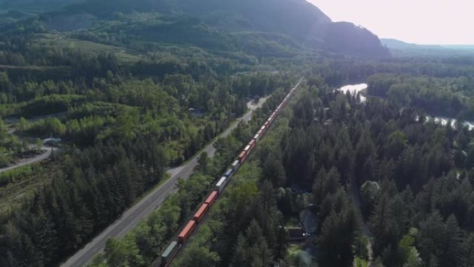 载有集装箱的货物火车在附近山区通过铁路经过视频，火车后的前向摄像机运动。