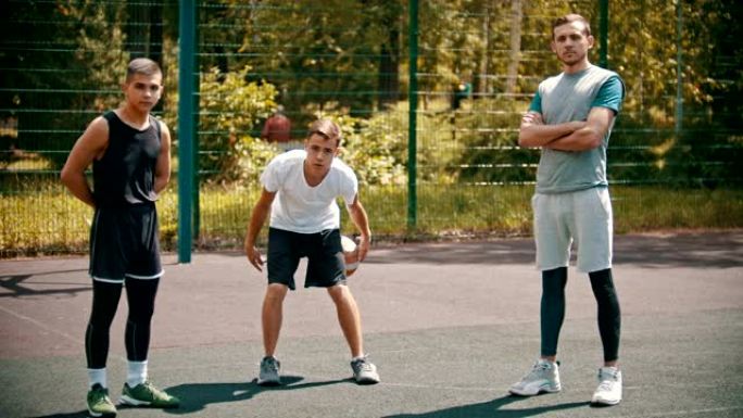 三名运动员站在室外篮球场上-一名运动员做保持运动-uppies