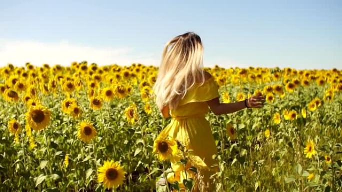 一个穿着黄色连衣裙的年轻女孩穿着向日葵穿过田野。慢动作