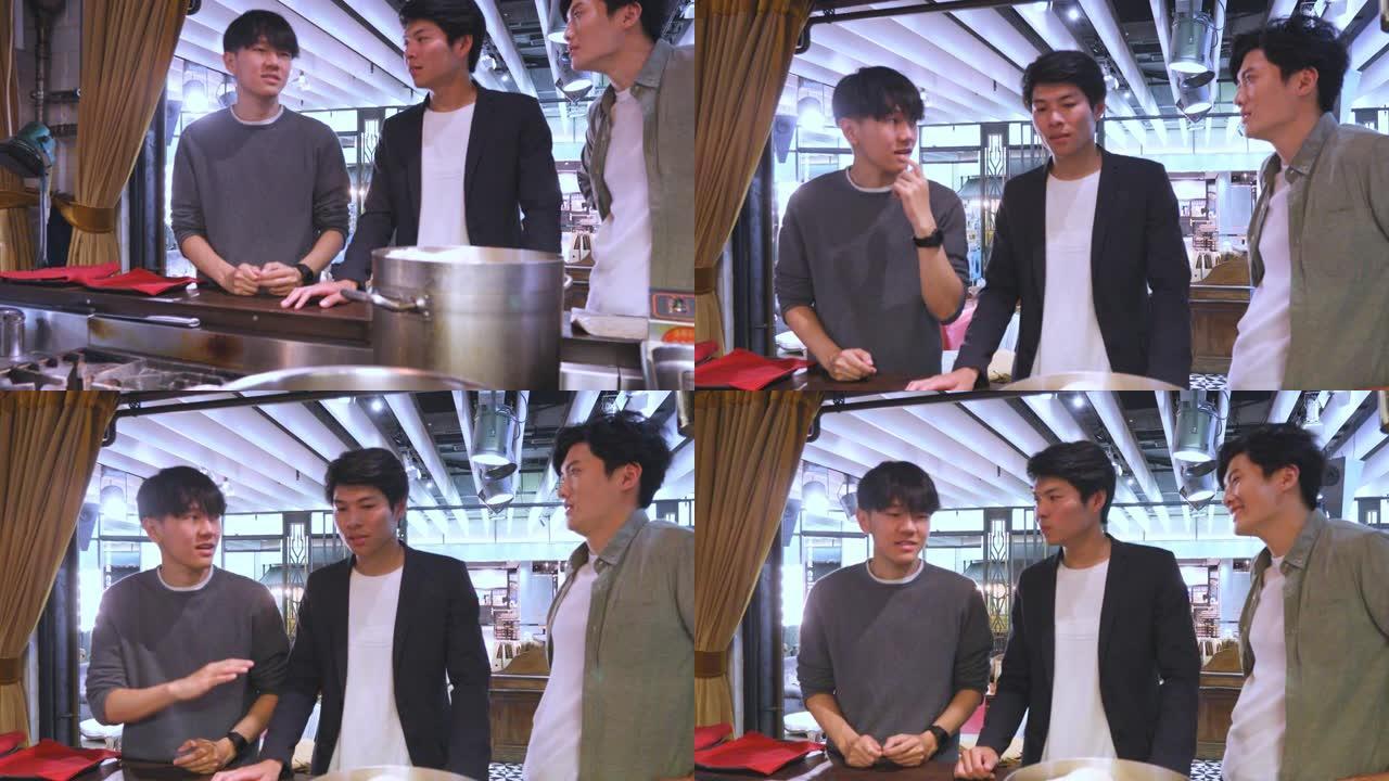 年轻的亚洲男子观看在餐厅烹饪的食物