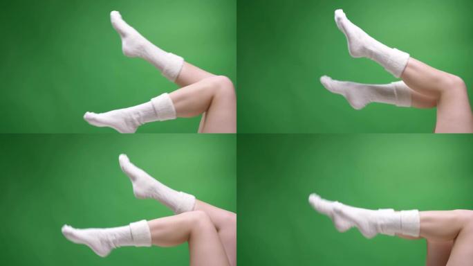 特写侧视图拍摄的女性青少年腿穿着可爱的白色短袜锻炼，背景孤立在绿色上