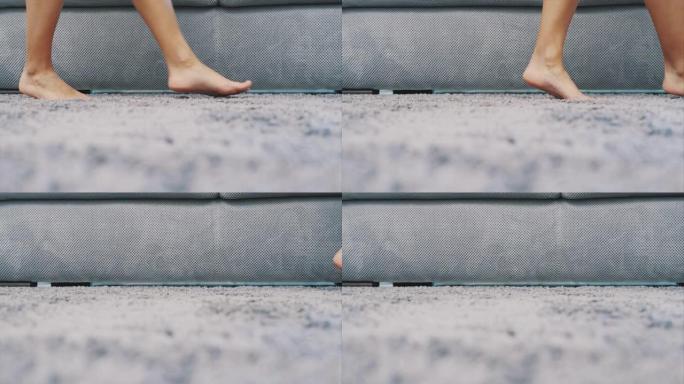 女人的腿在地板上的灰色地毯上行走。从上面看蓬松的地毯。现代风格。