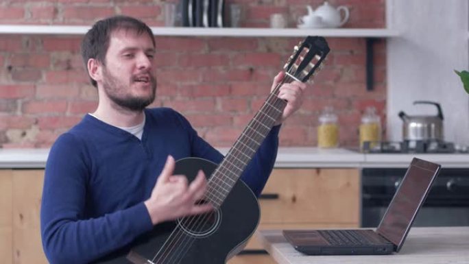 有趣的乐器演奏家男性学习吉他使用笔记本电脑进行在线视频培训，享受音乐