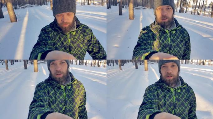 大胡子男子在冬季公园为他的博客拍摄手机视频，男性肖像