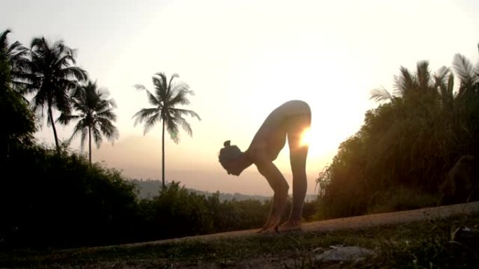 瑜伽老师在日出时将身体弯曲到膝盖慢动作