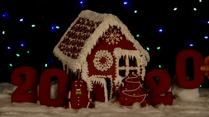 手工制作的可食用姜饼屋，手工添加零2020年铭文，小矮人，新年树，雪装饰，花环背景照明
