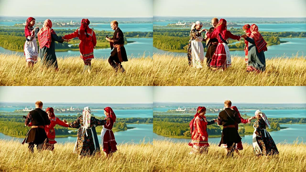 穿着传统俄罗斯服装的年轻合奏在河流和岛屿的背景下在球场上跳舞。