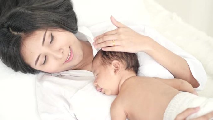 亚洲男婴睡在美丽的母亲身上。母亲节概念。