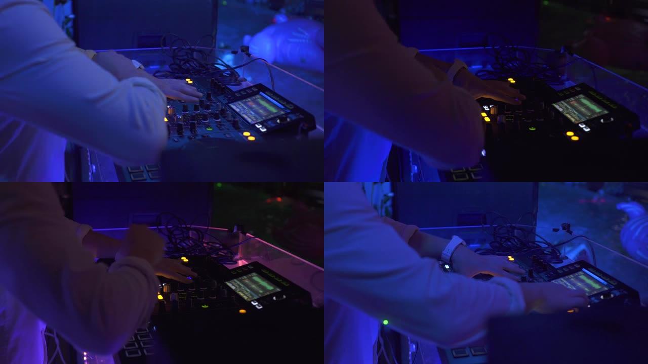 Dj在夜总会五颜六色的灯光下在调音台上播放音乐。迪斯科派对的DJ混音器和音乐控制台。彩色照明的唱片骑
