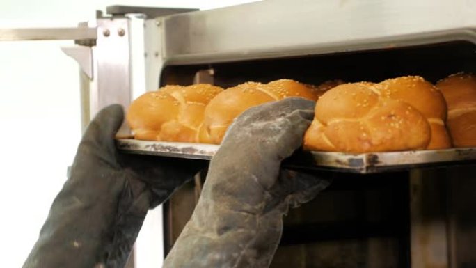 在烤箱里烤面包。厨房工人从面包店的烤箱中取出面包。