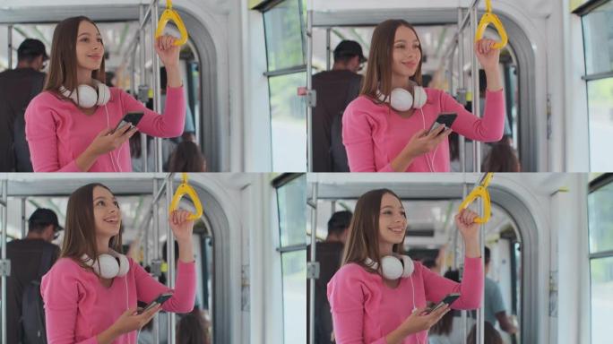 年轻的女性乘客在公共交通工具上享受旅行，站在现代电车上的智能手机上。