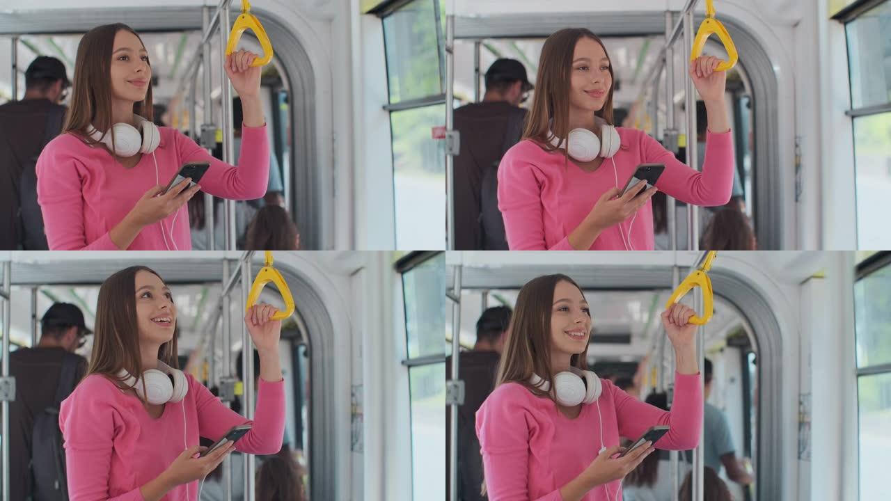 年轻的女性乘客在公共交通工具上享受旅行，站在现代电车上的智能手机上。