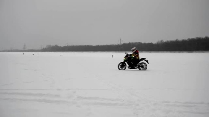 摩托车手职业运动员在雪地里骑冬季赛道，侧视图。
