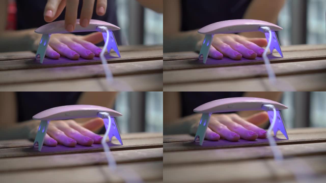 特写镜头，一名妇女使用在紫外线下变硬的凝胶抛光剂修指甲