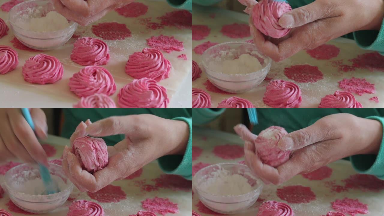 一个女人用刷子将糖粉涂在棉花糖上。接下来是不同色调的准备好的棉花糖。