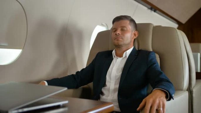 年轻的企业家睡在私人飞机内舒适的扶手椅上
