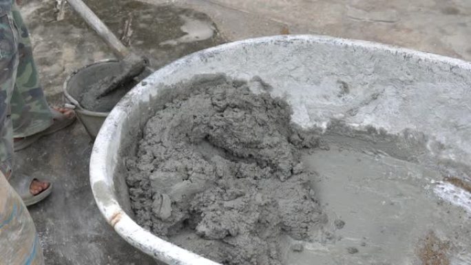 工人在水草中搅拌水泥以进行施工。建筑工人将水和沙子放在混凝土搅拌水泥上