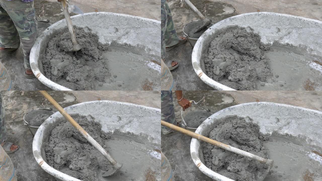工人在水草中搅拌水泥以进行施工。建筑工人将水和沙子放在混凝土搅拌水泥上