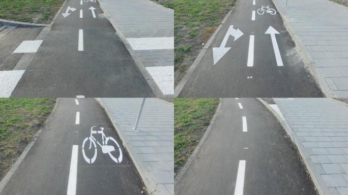 在新的黑色柏油马路上，地面上有涂漆白色自行车标志或符号和箭头的自行车道