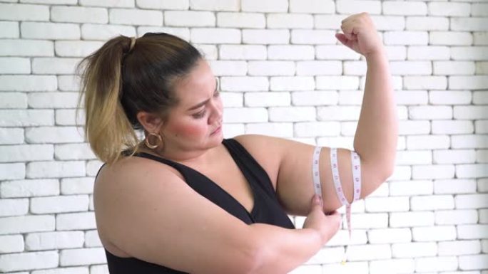 泰国超重妇女用卷尺测量手臂