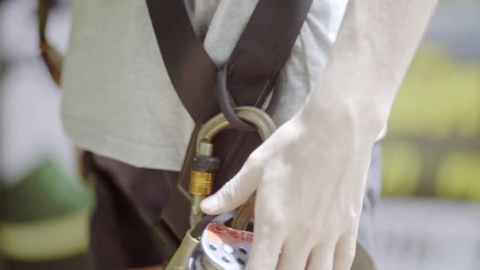3张手的男人准备在冒险公园的滑索上骑行的设备。