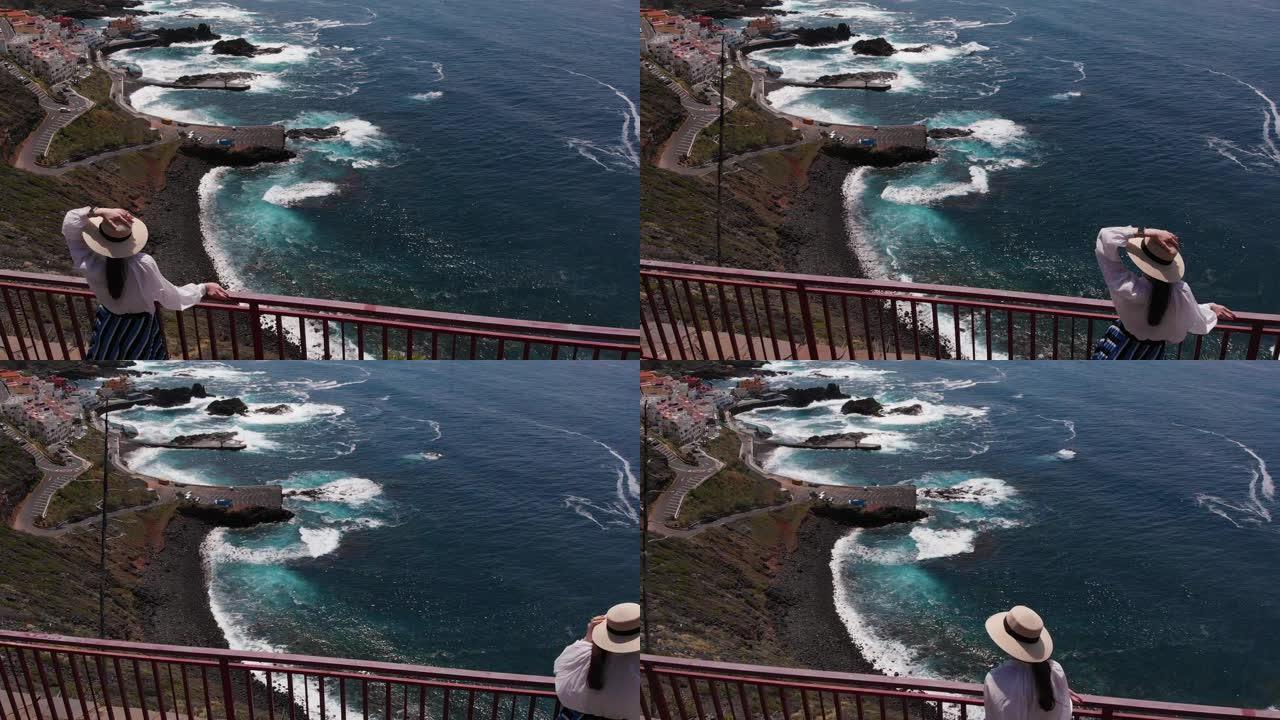 航拍镜头 -- 时尚现代的戴帽子女孩站在大西洋一个岛屿海岸的悬崖边缘