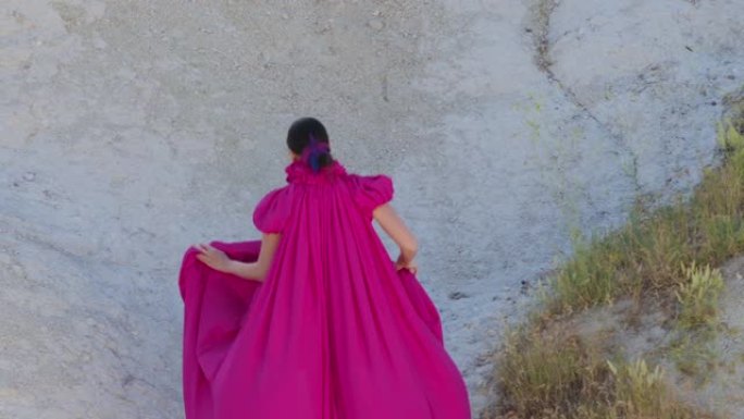 年轻的高个子女孩模特穿着紫色长裙在山上奔跑