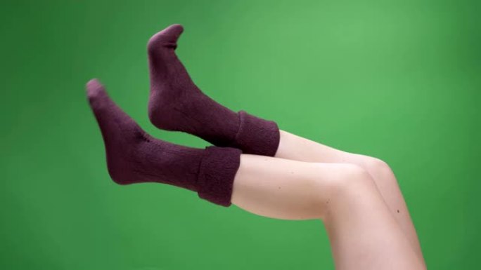 穿着可爱的红色短袜的女性青少年腿特写镜头，背景孤立在绿色上嬉戏地移动