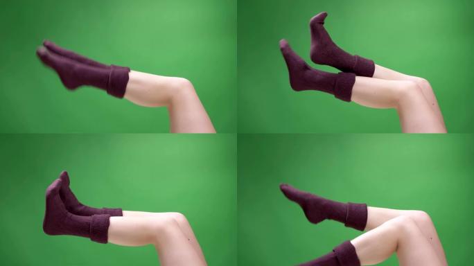 穿着可爱的红色短袜的女性青少年腿特写镜头，背景孤立在绿色上嬉戏地移动