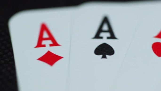扑克牌顶部的宏观细节拍摄，所有四个ace hearths钻石空间交叉躺在大象上，同时随着纸牌从侧面慢
