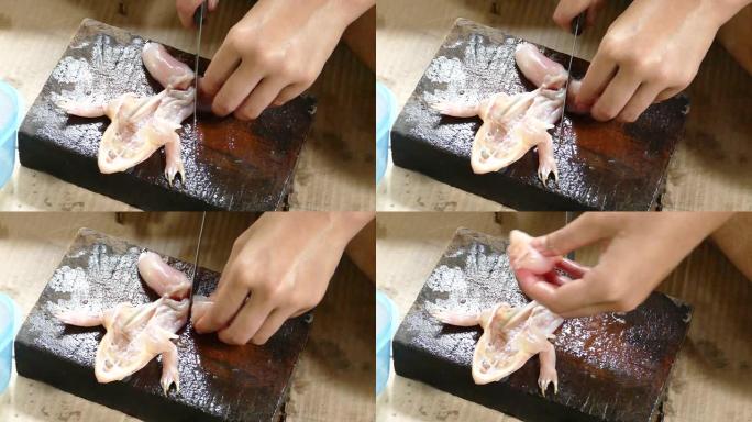 亚洲泰国妇女的手用刀在砧板上切割新鲜青蛙