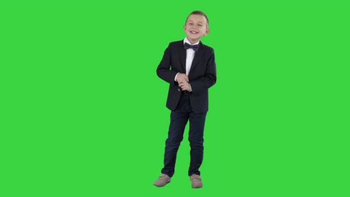 穿着正式服装的小男孩在绿色屏幕上说话和微笑，色键
