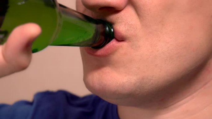 特写。高加索人喝绿色瓶子里的啤酒