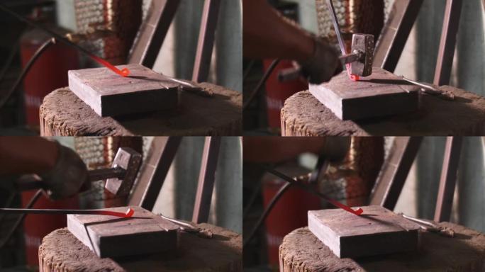 铁匠在锻造车间的铁锤铁棒上弯曲铁棒。