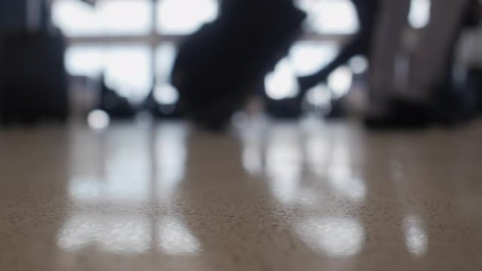 旅客在镜头前走时无法对焦，被大型机场窗户映入轮廓，聚焦在地板上