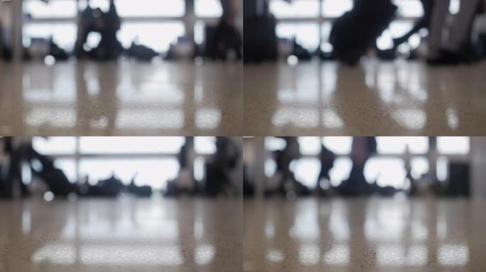 旅客在镜头前走时无法对焦，被大型机场窗户映入轮廓，聚焦在地板上
