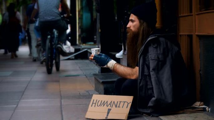无家可归的人，用 “人道” 纸板在拥挤的街道上乞讨