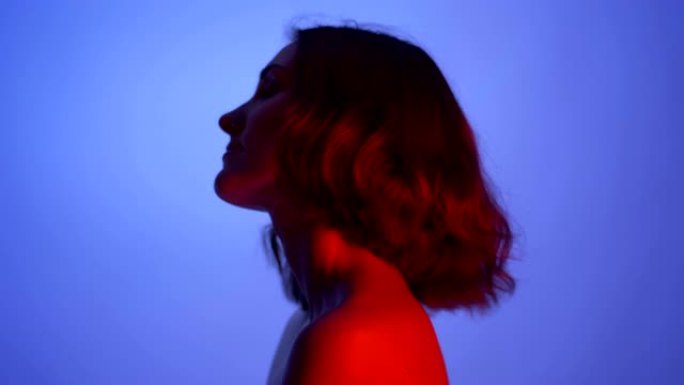 特写侧视图拍摄的年轻性感的女性赤裸的肩膀与霓虹灯蓝色和红色的背景