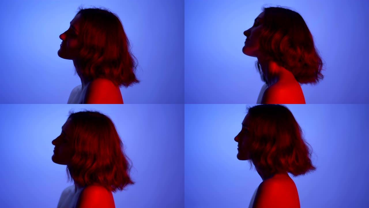 特写侧视图拍摄的年轻性感的女性赤裸的肩膀与霓虹灯蓝色和红色的背景