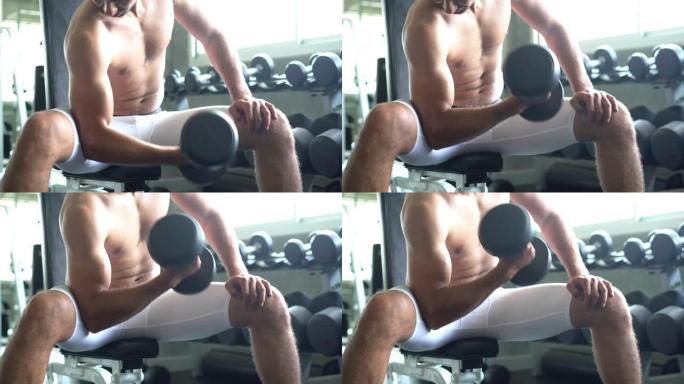 运动员的肌肉手臂在做哑铃卷发，男人在健身房一次锻炼肌肉一个代表强壮的二头肌。