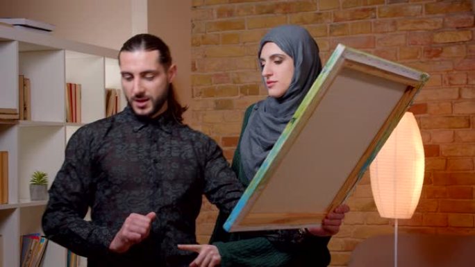 年轻迷人的穆斯林夫妇在室内新买的公寓里定居的特写镜头。男人和女人建议在哪里交照片