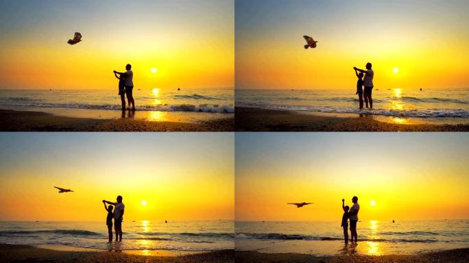 父子俩在海边放风筝，有着美丽的橙色天空日落。Steadicam射击