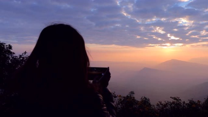 亚洲女子用智能手机拍摄有雾的山景照片，概念女子单人旅行