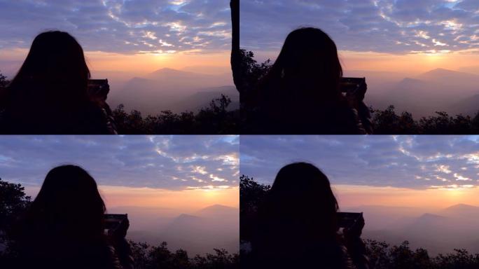 亚洲女子用智能手机拍摄有雾的山景照片，概念女子单人旅行