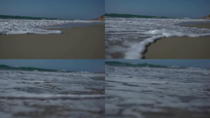 低角度视角和慢动作拍摄海浪和海泡海岸。