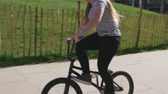 年轻女子BMX骑手在现代城市环境中骑自行车