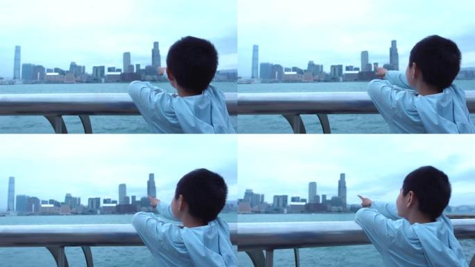 可爱的男孩指着香港的摩天大楼