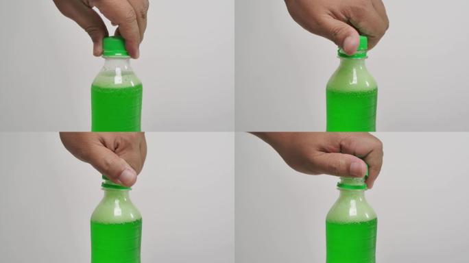 一个男人打开白色背景上的绿色起泡软饮料瓶盖的特写镜头。