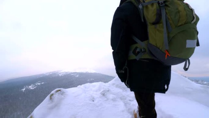 一个年轻人，一个游客，站在白雪皑皑的山边，敬佩山顶。