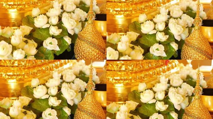 祭坛上的鲜花和金色装饰。美丽的白莲花和金色的皇家装饰品放在泰国的传统祭坛上。君主制的象征。
